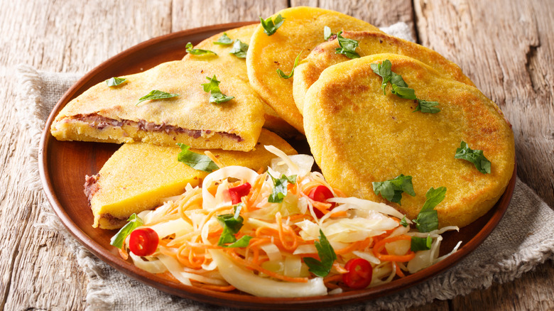 Pupusas served with curtido on wooden table