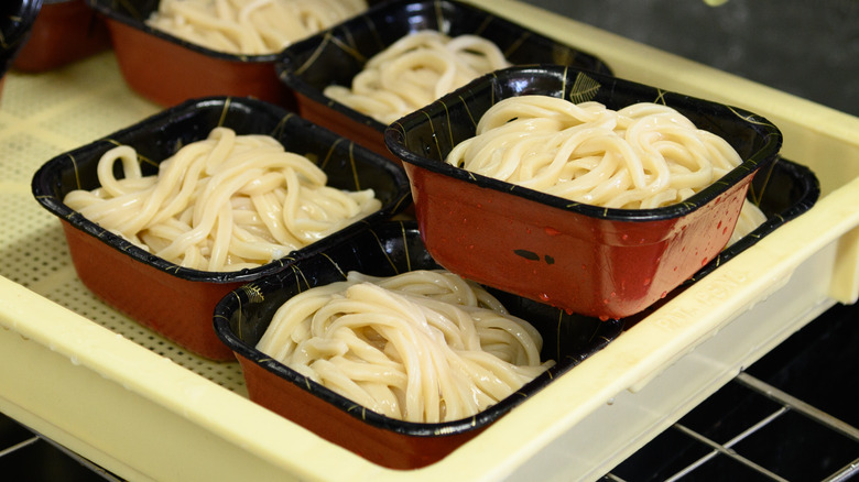 Plates of udon noodles being prepared