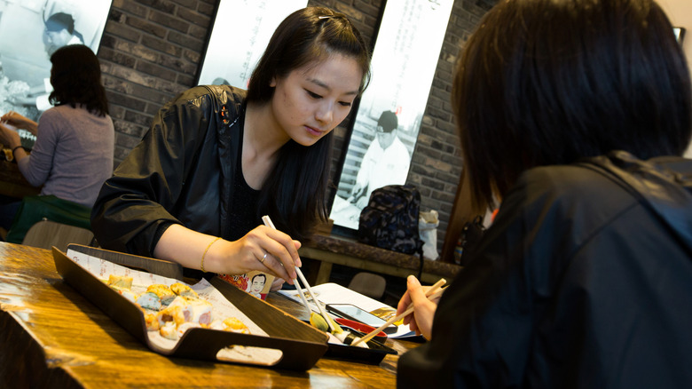 Two people eating sushi in a restaurant