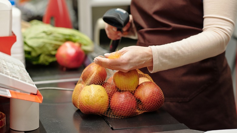 Cashier scanning bag of apples
