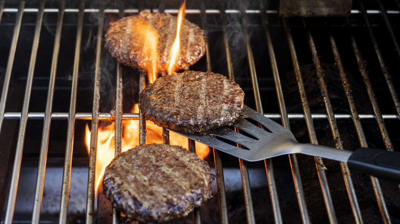 Hamburger patties on flaming grill