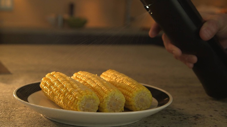 Biem spraying butter on corn