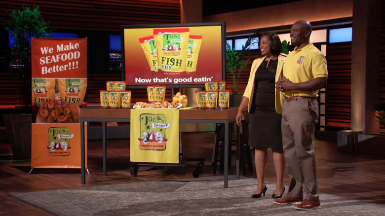 Founders of Joe's Gourmet Fish Fry standing next to a product display and sample platter on Shark Tank.