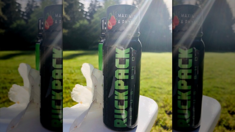 A bottle of RuckPack Combat Nutrition with lens flare and a white flower