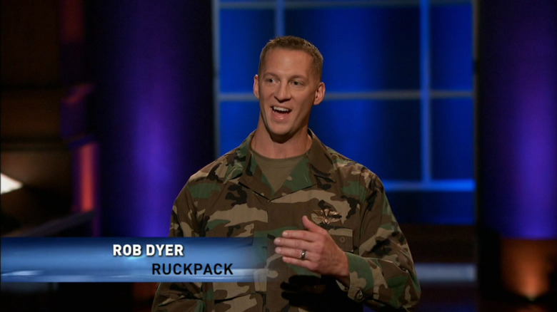 Dyer in green camouflage fatigues with a chyron saying "Rob Dyer, RuckPack"