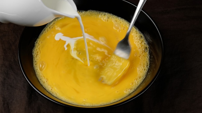 pouring milk into scrambled eggs