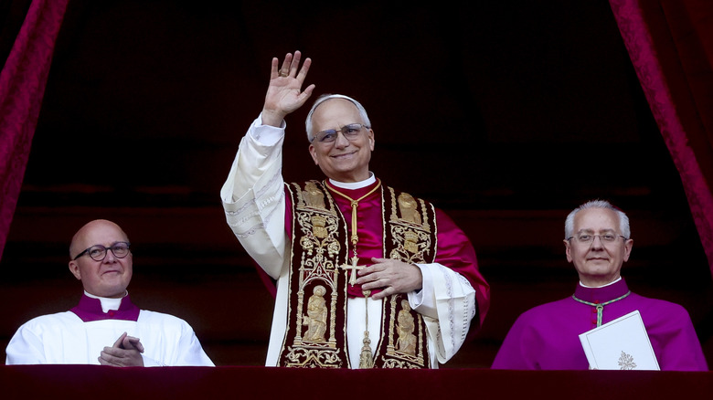 Newly elected Pope Leo XIV, Cardinal Robert Francis Prevost, greets a crowd flanked by clergymen