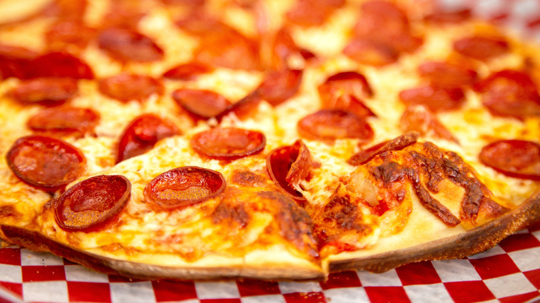 Thin crust pepperoni pizza on checkered table