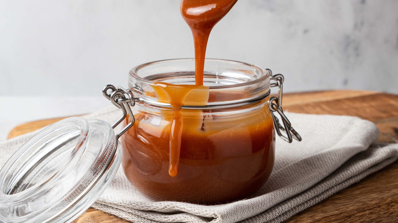 Caramel sauce dripping into a glass jar