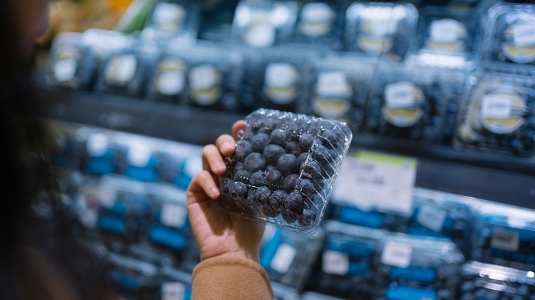 Hand holding a package of blueberries
