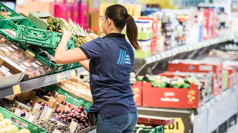 Aldi employee restocking produce 