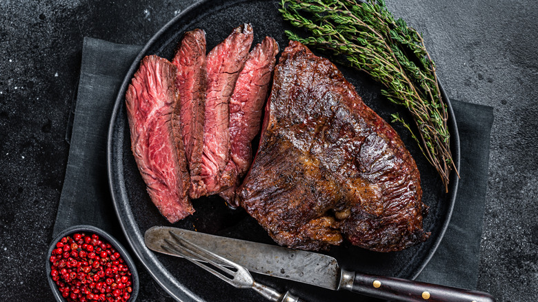 Hanger steak in wooden tray with herbs.