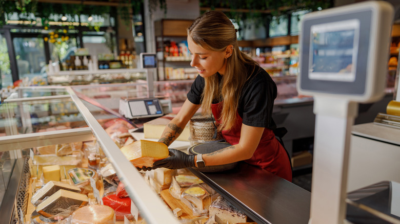 Employee handling cheese from cheese case.