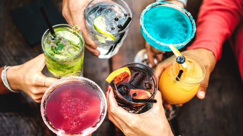 people holding cocktails and toasting