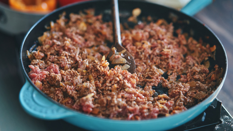 Ground meat cooking in blue skillet