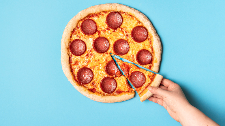 Hand grabbing pepperoni pizza