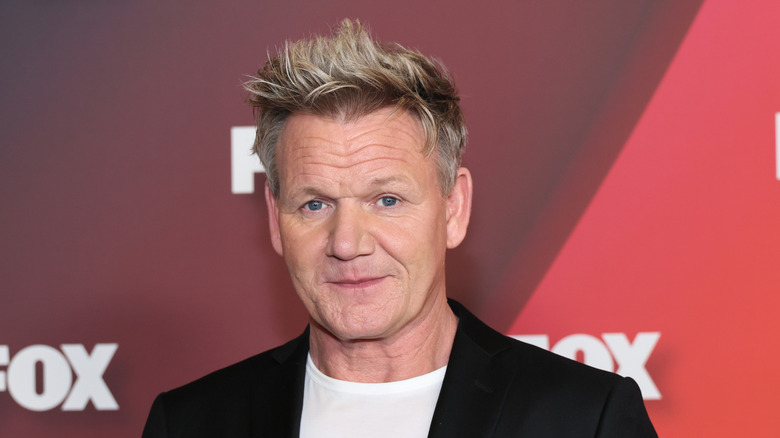 Gordon Ramsay posing at an event in a black blazer with a white top underneath
