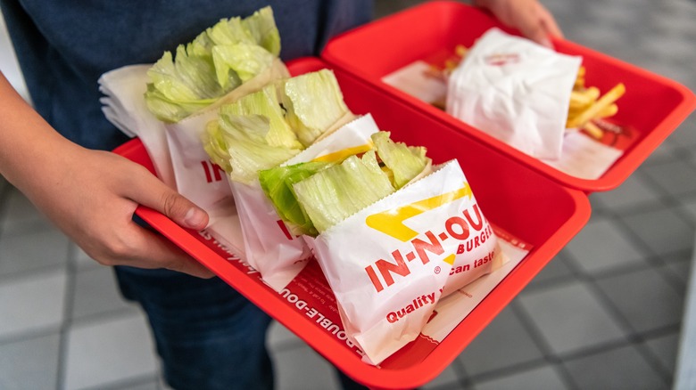 customer holding lettuce wraps and fries on trays
