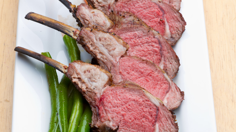 lamb cooked medium rare on plate with green beans 