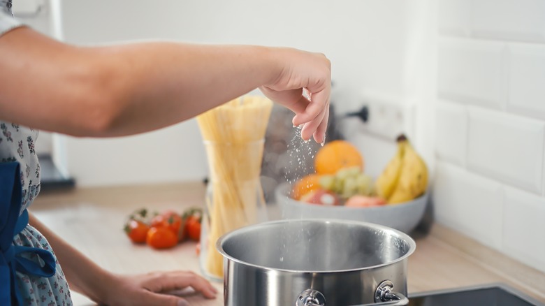 adding salt to a pot of water