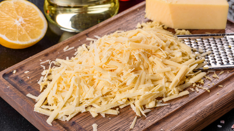 Freshly shredded cheese on a wooden cutting board