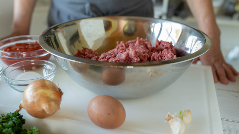 A person stands before a counter featuring some basic meatloaf ingredients