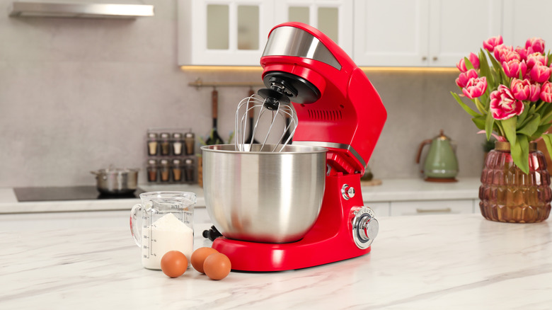Red stand mixer on a white marble countertop