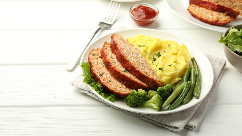 Nicely plated meatloaf with mashed potatoes, micro greens, broccoli, and green beans