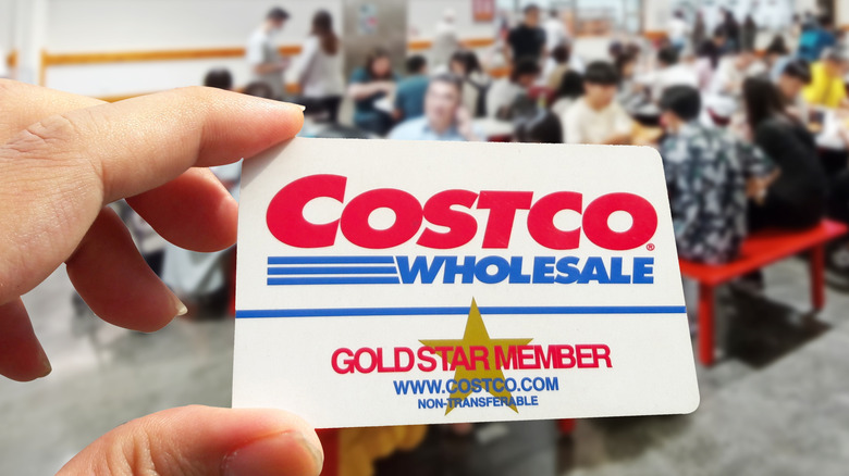 Hand holding up Costco Gold Star Membership card in Costco food court