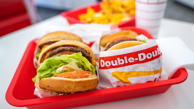 A red tray with burgers, some wrapped in white, red and yellow paper with writing 