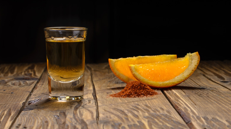 A shot glass with orange slices and worm salt.