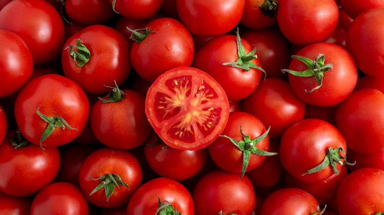 Half a tomato on pile of whole tomatoes