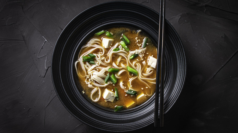 A bowl of udon noodle soup with chopsticks