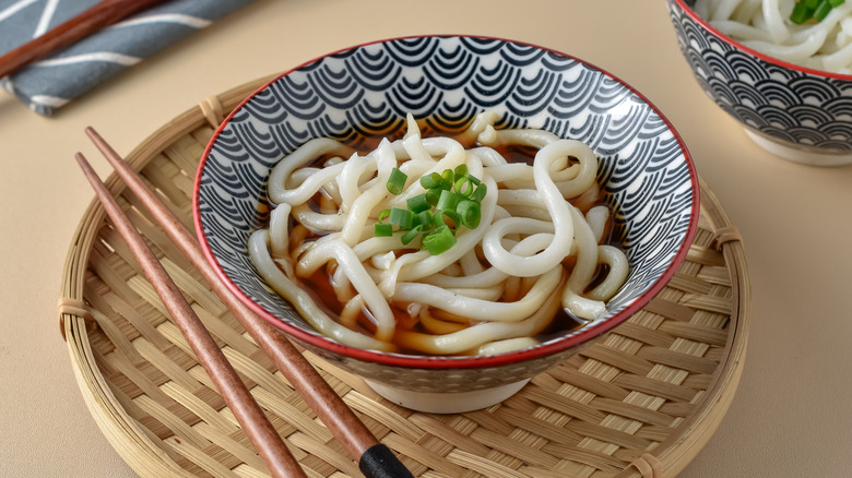 A bowl of udon noodle soup with chopsticks
