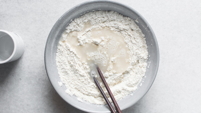 Flour and water being stirred with chopsticks in a bowl