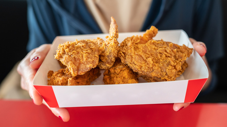 woman holding box of fried chicken