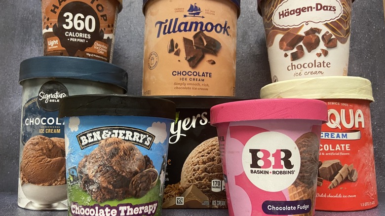 Several brands of chocolate ice cream in cartons, stacked