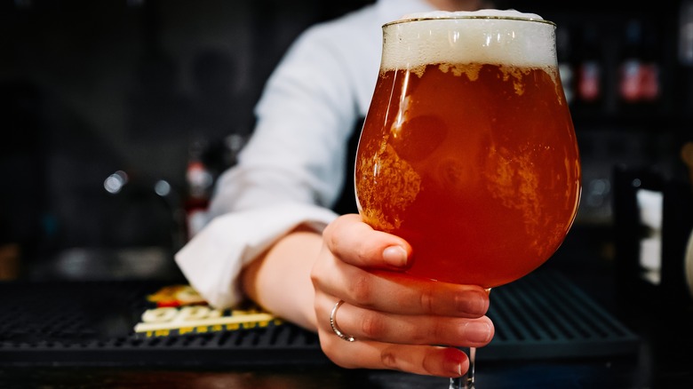 Bartender holding beer in tulip glass