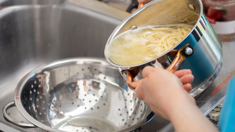 Pouring a pot of noodles into a colander