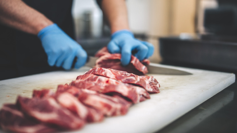 Butcher cutting meats on board