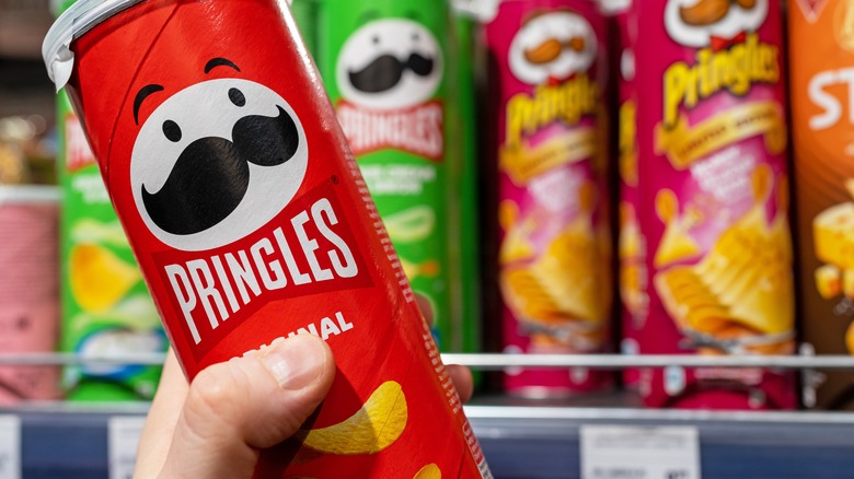 A person picks up a tube of Pringles