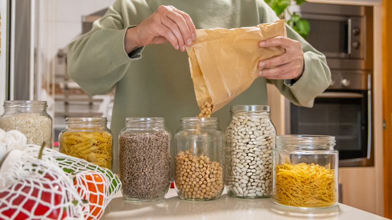 Close-up on person filling glass jars with dry goods
