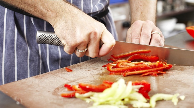 Hands slicing red pepper 