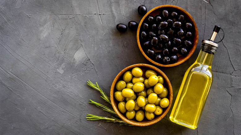 Bottle of oil surrounded by black and green olives