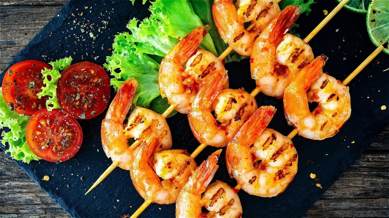 Grilled shrimp skewers on black platter 