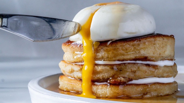 Poached egg sitting on top of a stack of pancakes