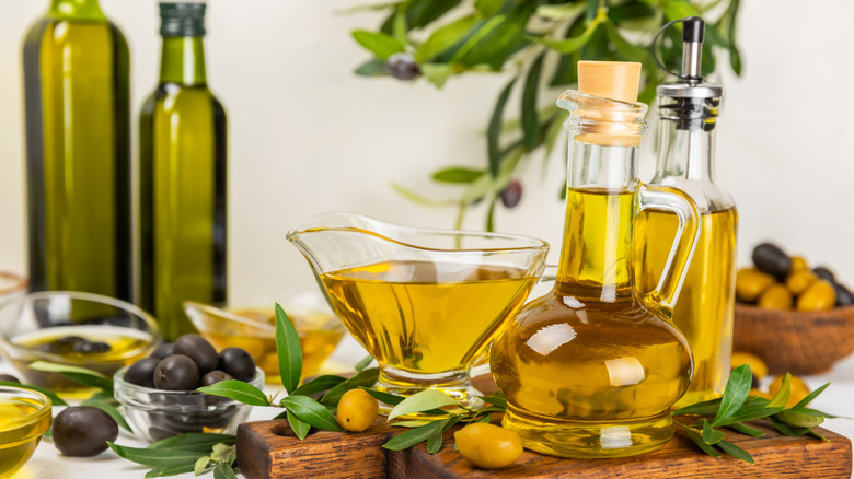 Bottles of olive oil with olives and a blurred kitchen background