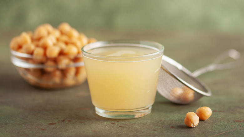 Glass of aquafaba and chickpeas on table