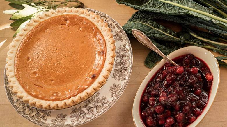 pumpkin pie with a bowl of cranberry sauce