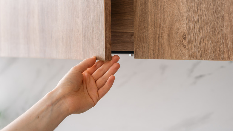 Person opening wooden cabinet